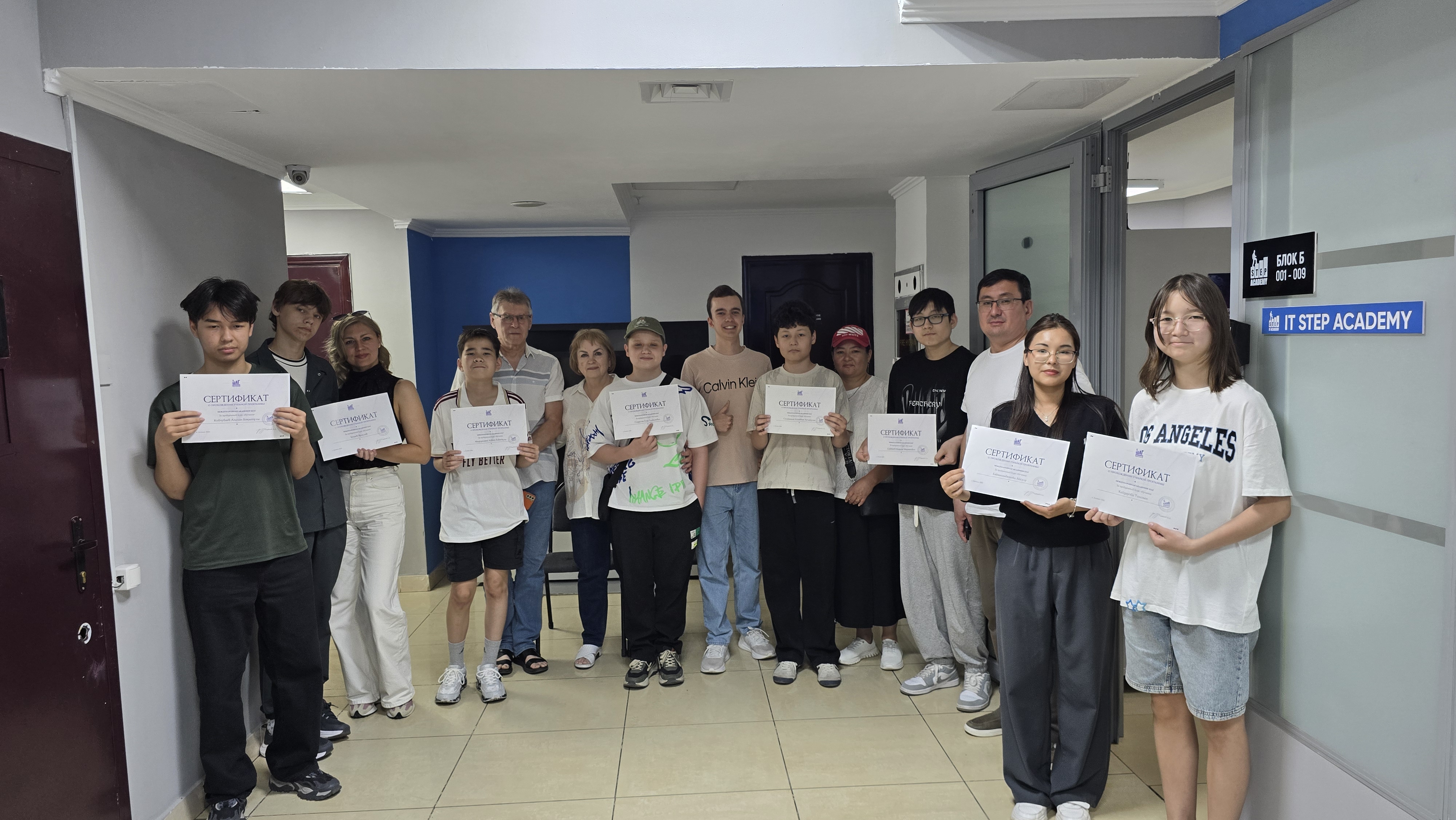 Students and staff holding certificates in the hallway at ITSTEP Academy
