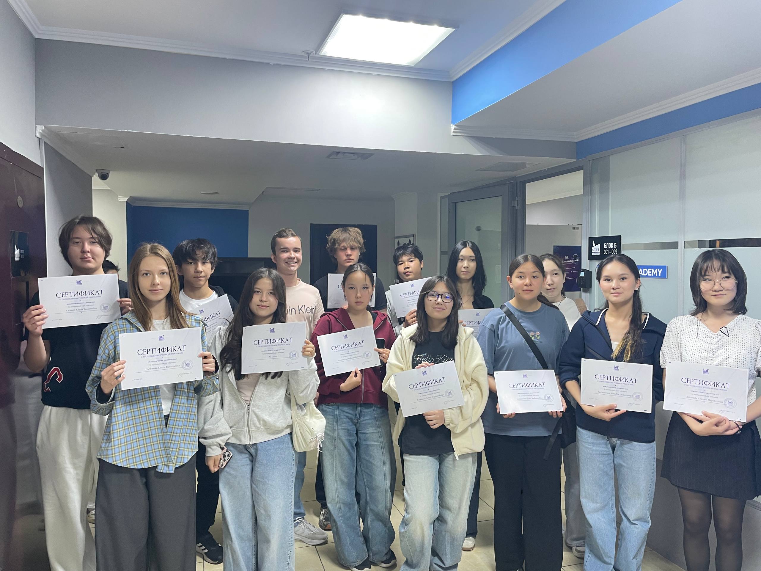 A large group of students and staff holding certificates at ITSTEP Academy